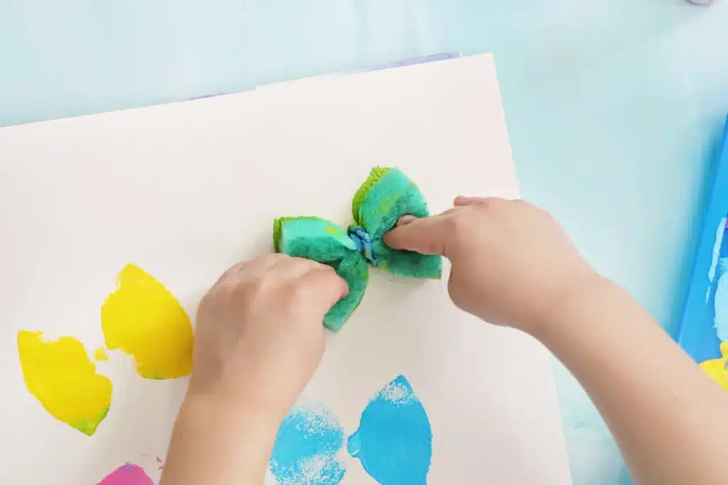 Sponge Painted Butterflies - Cultivating Brilliant Minds a kid stamping down a sponge with paint on it