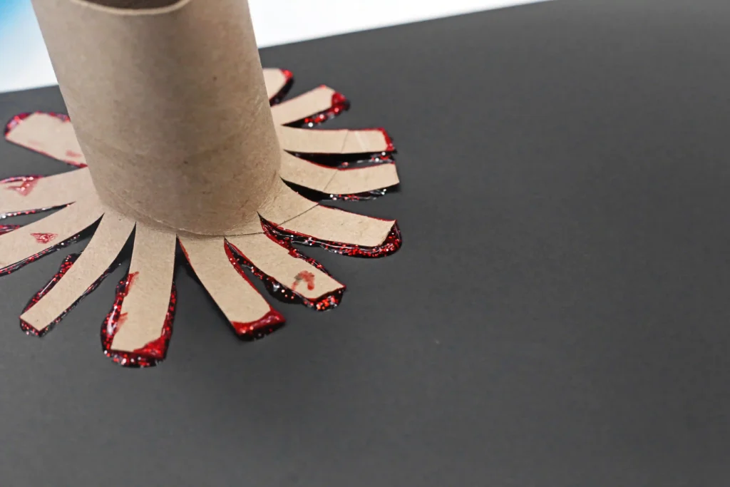 Toilet Paper Roll Firework Craft - Cultivating Brilliant Minds a toilet paper roll that has been cut to look like a firework with red paint on it stamped down on black paper