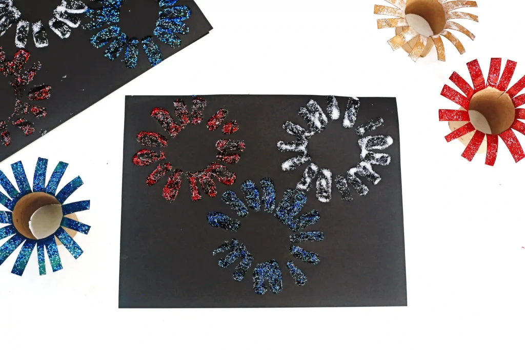 Toilet Paper Roll Firework Craft - Cultivating Brilliant Minds a black paper with glitter paint fireworks stamped on