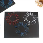 a black paper with glitter paint fireworks stamped on