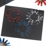 a black paper with glitter paint fireworks stamped on
