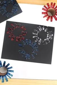 a black paper with glitter paint fireworks stamped on