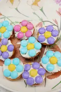 a vanilla wafer with icing and pastel m&ms in the shape of a flower