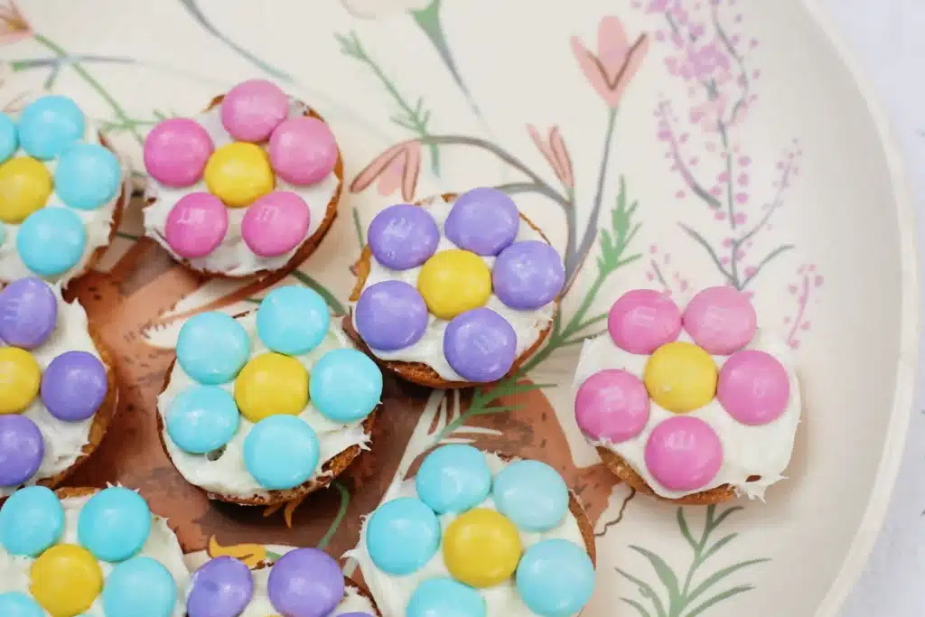 Vanilla Wafer Flower Cookies - Cultivating Brilliant Minds a vanilla wafer with icing and pastel m&ms in the shape of a flower