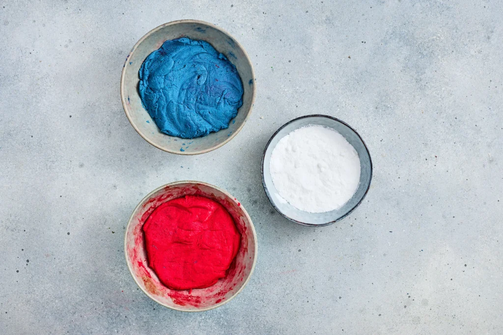 cookie dough dyed red and blue next to powdered sugar