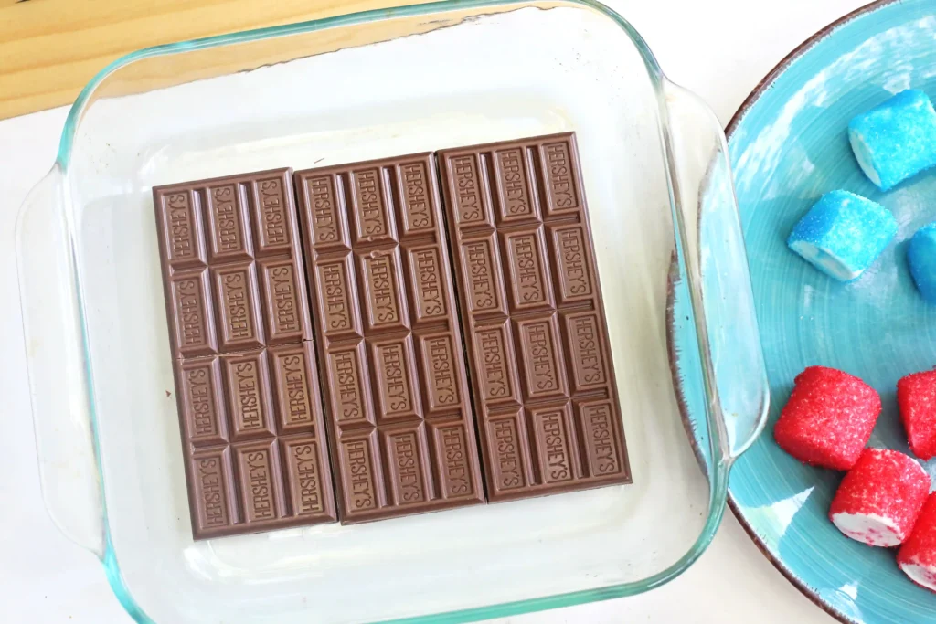 Milk chocolate Hershey's bar arranged in a glass baking dish, with a turquoise plate nearby.