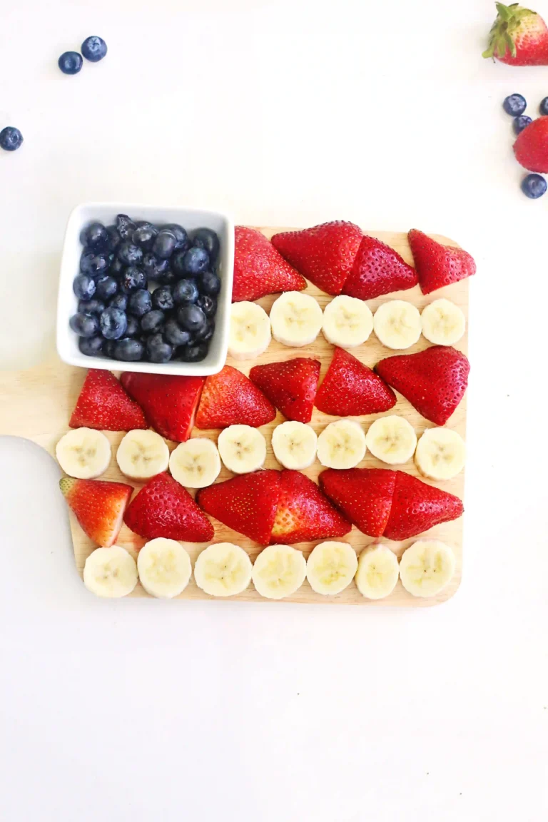 an American Flag Fruit Charcuterie Board that uses blueberries, bananas, and strawberries to make the american flag