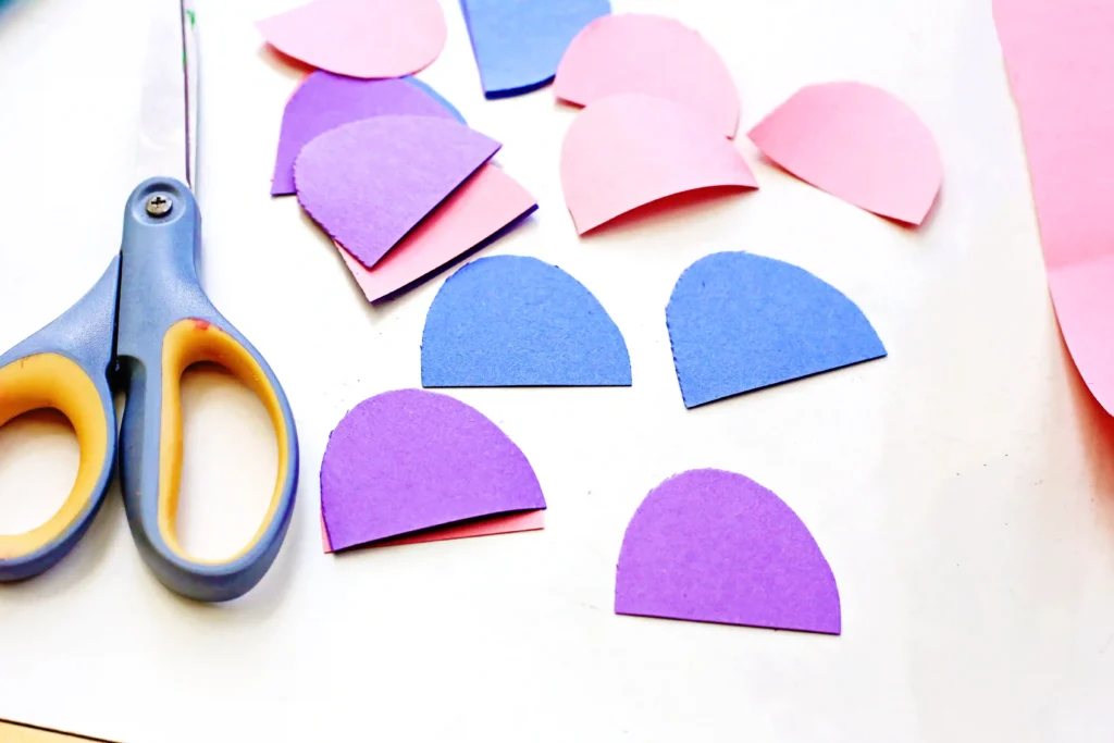 half circle cut outs of pink, blue, and purple construction paper