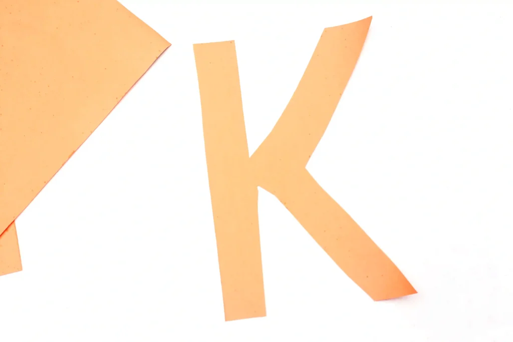 letter k cut out of orange construction paper