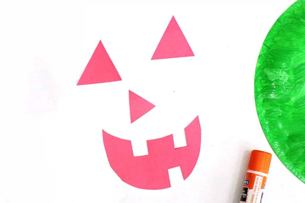 a jack-o-lantern face cut out of red construction paper for this summerween activity