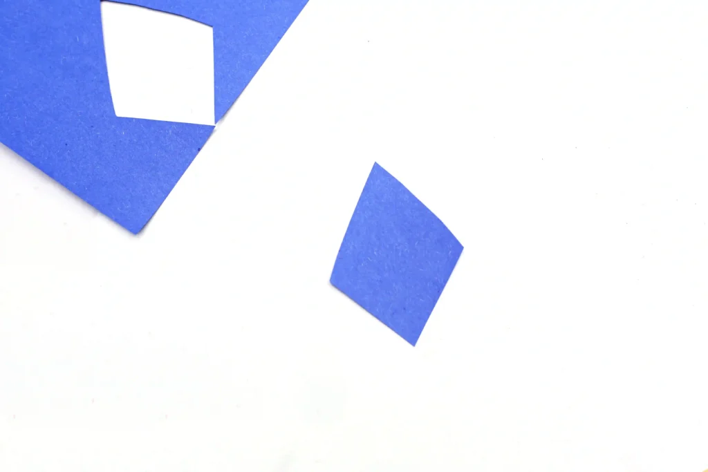 a diamond cut out of blue construction paper to make the kite paper craft for kids