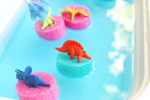 pool noodle slices with toy dinosaurs on top in blue water