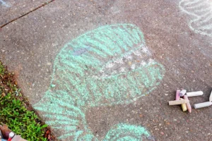Colorful sidewalk chalk drawing on pavement of a dinosaur
