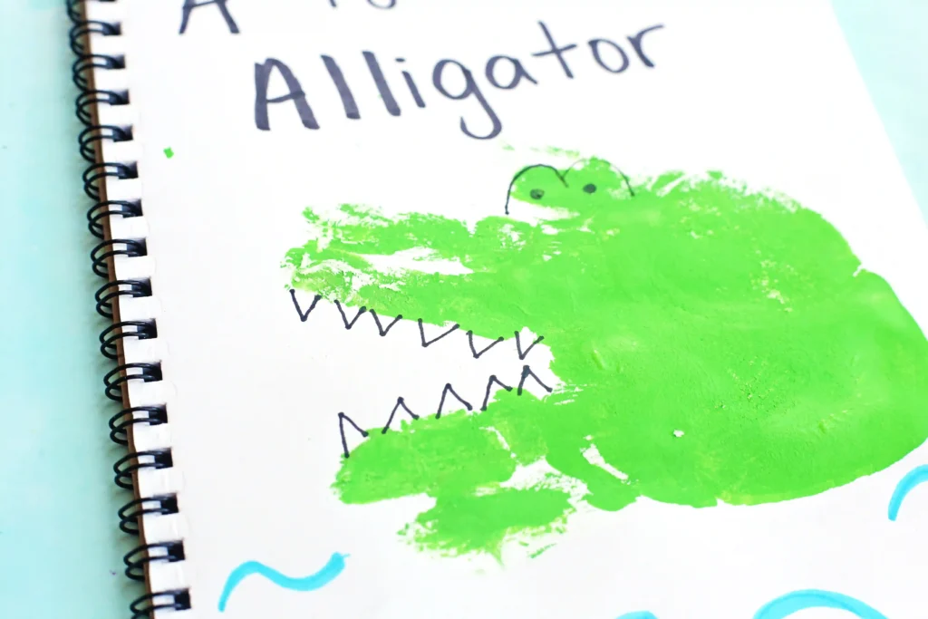 an alligator craft that is a green handprint decorated to look like an alligator in water with writing above it that reads "A is for Alligator"