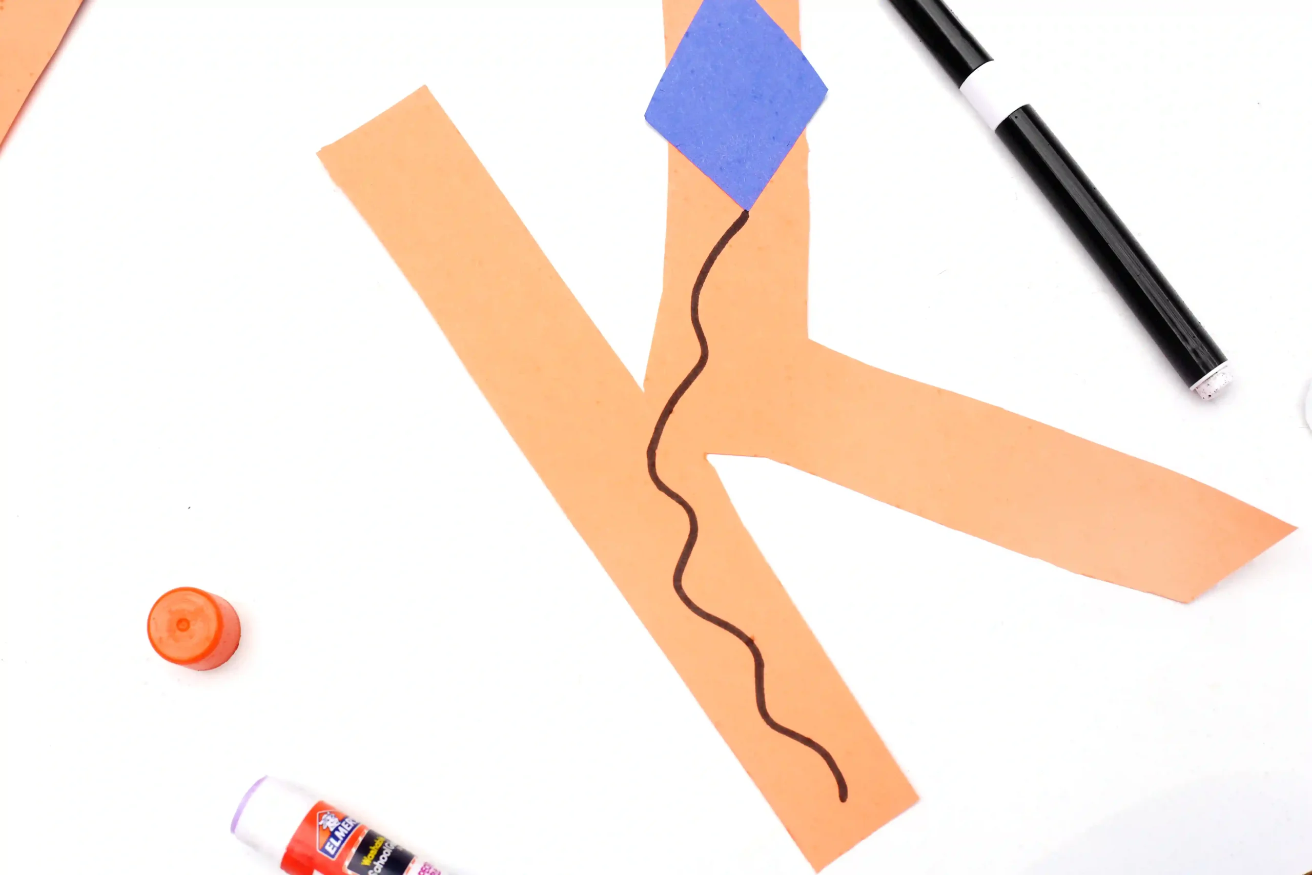 construction paper cut into a letter k with a blue diamond for a kite and a string drawn on with marker