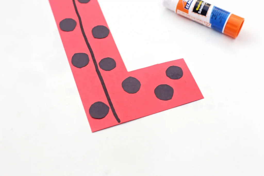 a letter l cut out of red construction paper with black polka dots