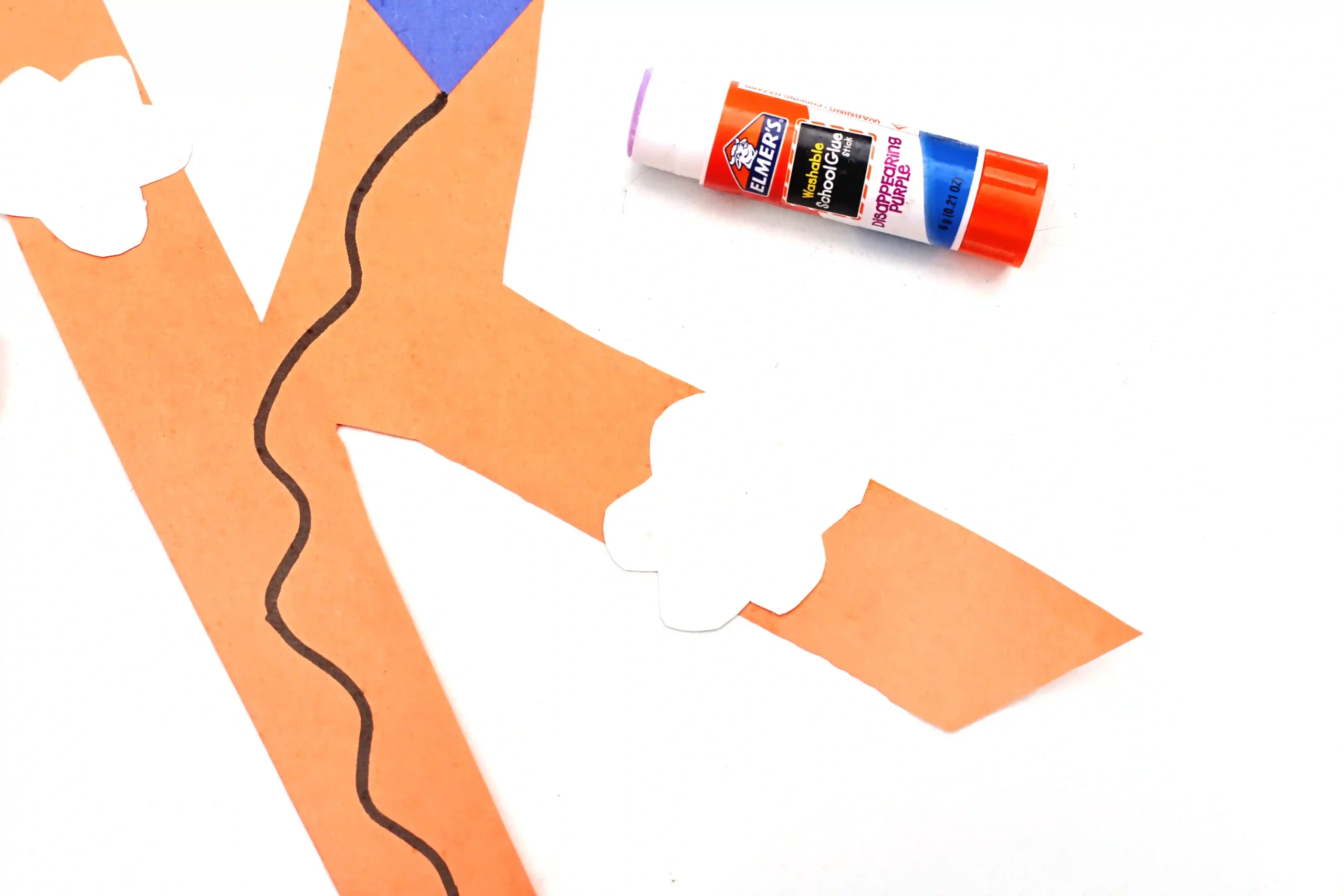 a letter k cut out of construction paper with a kite and clouds