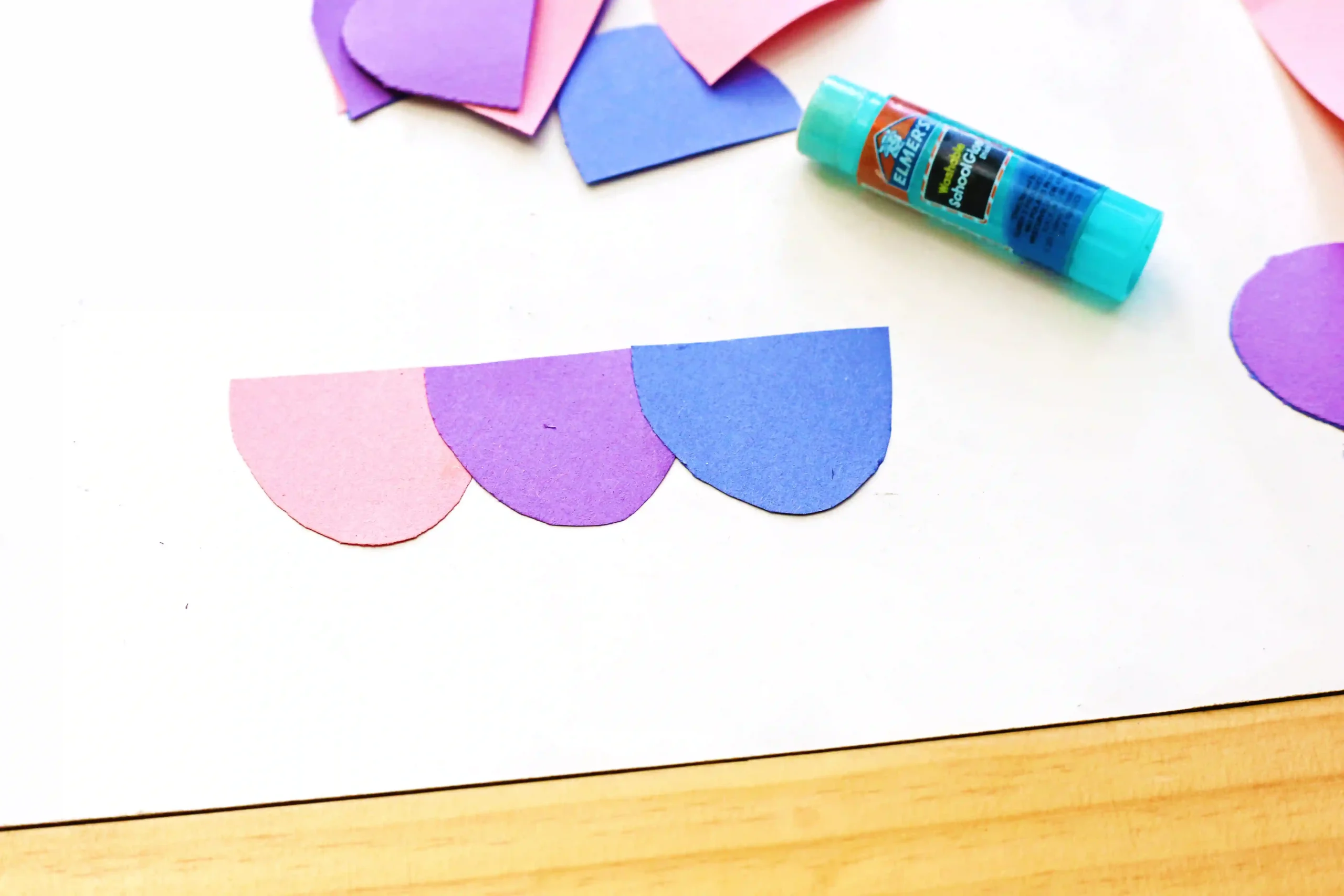 half circles cut out of purple, pink, and blue construction paper glued together