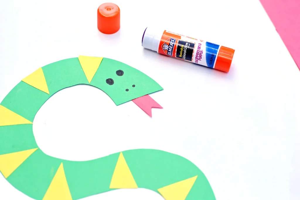 an alphabet activity that is a green letter S cut out of construction paper with yellow triangles, a red tongue, and eyes drawn on
