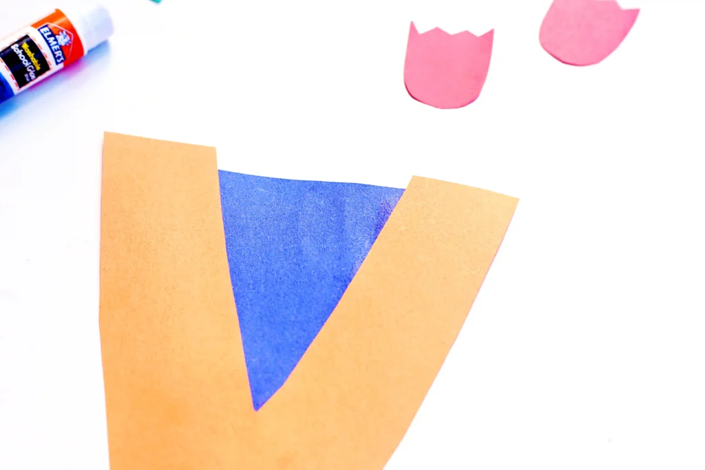 a letter v craft that has a letter v cut out of orange construction paper with a blue triangle glued on