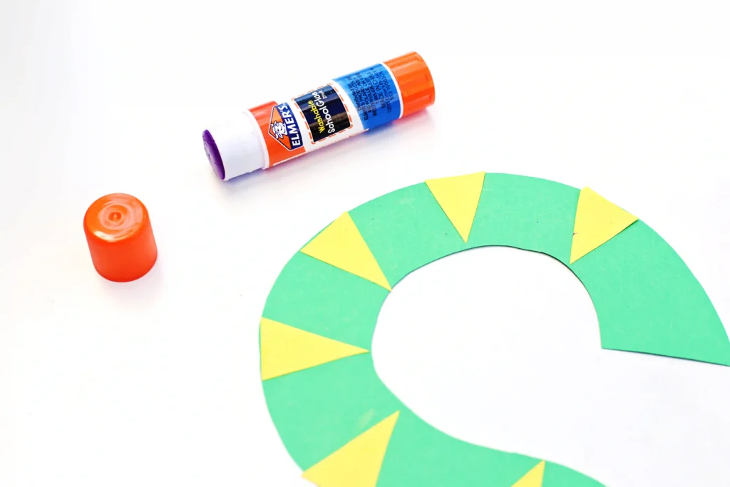 a letter S cut out of green construction paper with yellow triangles glued on to make the snake craft for kids