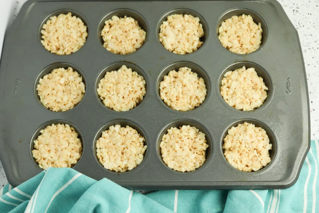 Muffin pan with twelve cups filled with rice krispie treats