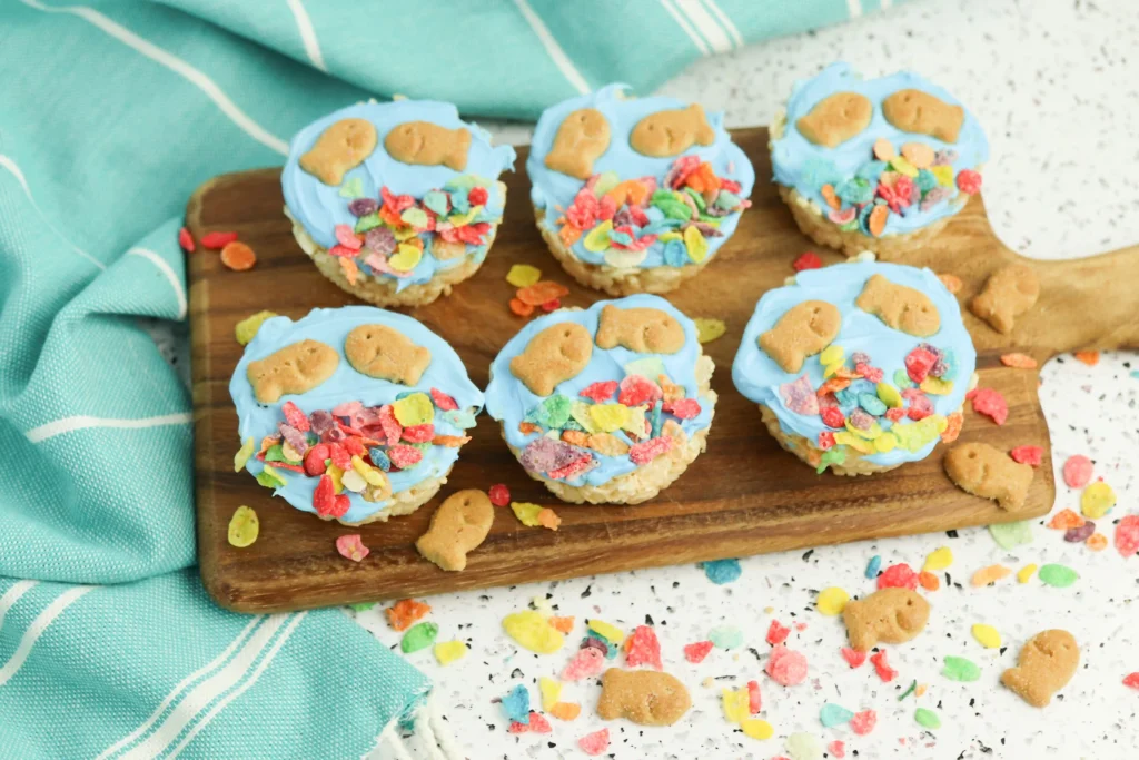 fish bowl rice krispie treats with goldfish crackers and fruity pebbles on a wooden cutting board