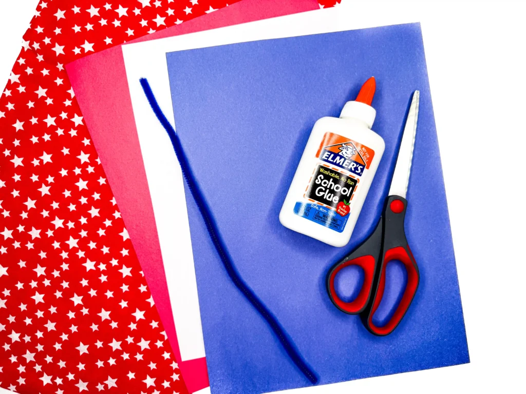 supplies for this patriotic craft: red, white, and blue construction paper, a blue pipe cleaner, glue, and scissors