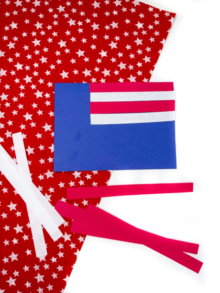 a memorial day craft: blue construction paper cut into a rectangle with red and white stripes to create an american flag