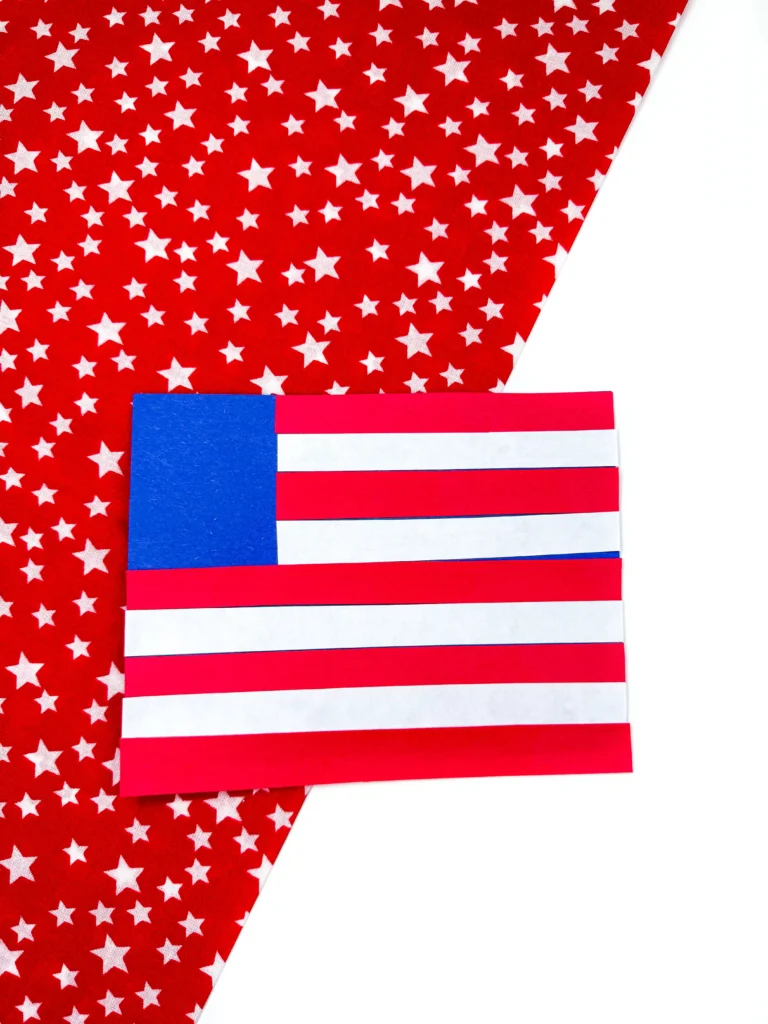 a fourth of july craft: blue construction paper cut into a rectangle with red and white stripes to create an american flag