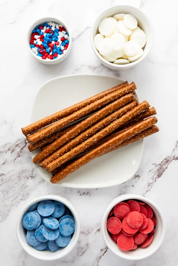 ingredients for the Patriotic Chocolate Dipped Pretzel Rods- pretzel rods, red white and blue star sprinkles, and red white and blue melting chocolate
