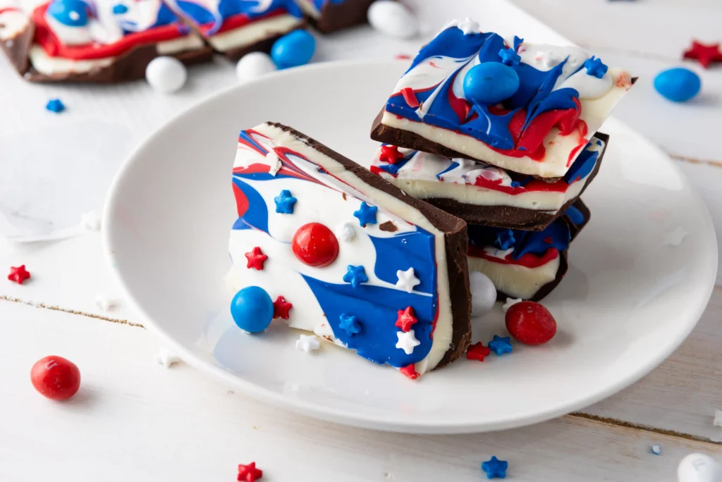 red, white and blue patriotic chocolate bark with patriotic m&ms on a white plate