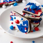 red, white and blue patriotic chocolate bark with patriotic m&ms on a white plate