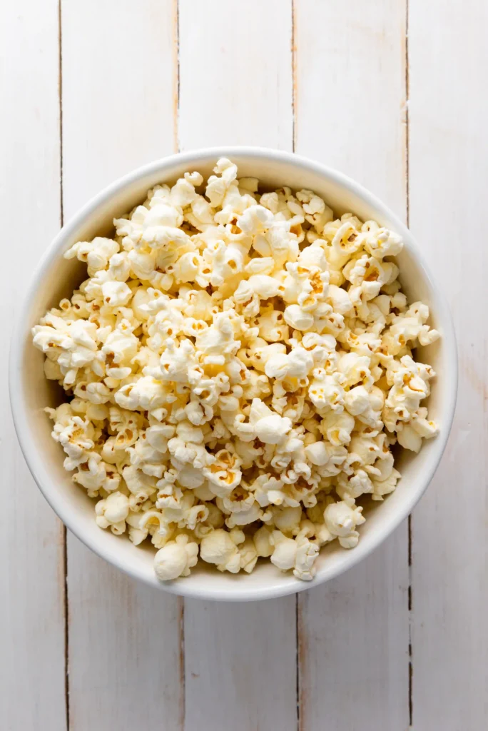 Patriotic Popcorn - Cultivating Brilliant Minds Bowl of white popcorn in a white dish on a light wooden surface, close-up view.