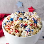 patriotic popcorn with red, white, and blue sprinkles, chocolate, and m&ms