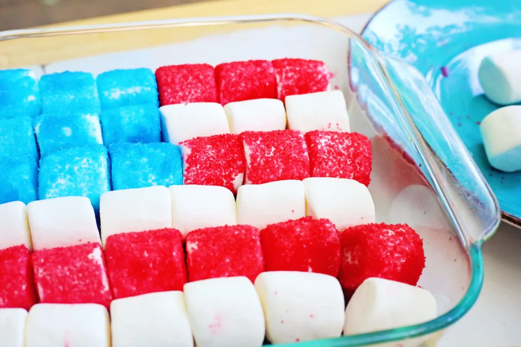 Close-up of blue, red, and white sugar-coated marshmallows arranged in a glass dish like the american flag, ready for serving