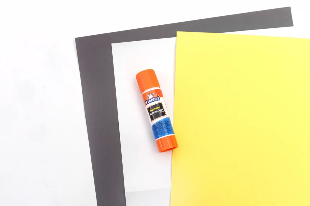 supplies for the letter n craft: black, white, and yellow construction paper and a glue stick