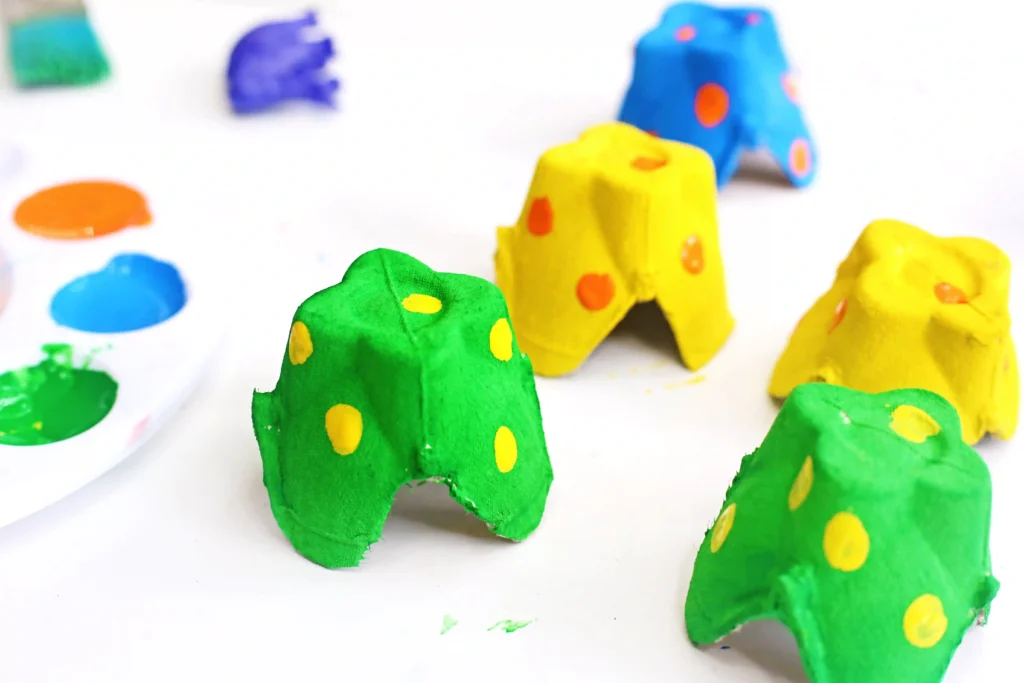 Colorful egg carton cups with yellow and orange polka dots on a white surface