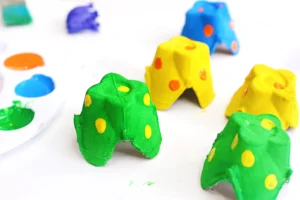 Colorful egg carton cups with yellow and orange polka dots on a white surface