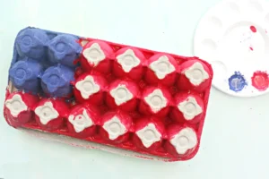 Close-up of a red dental impression tray filled with pink material and white tooth-shaped impressions; a blue tray is visible to the left.