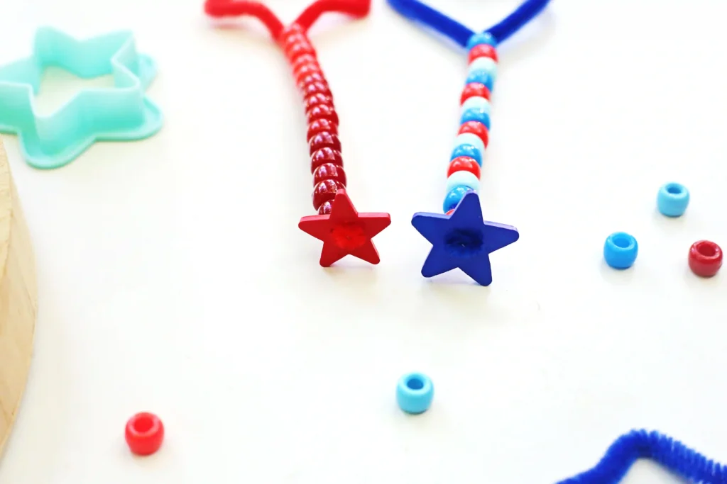 Two beaded pipe cleaners with red and blue star charms on the bottom