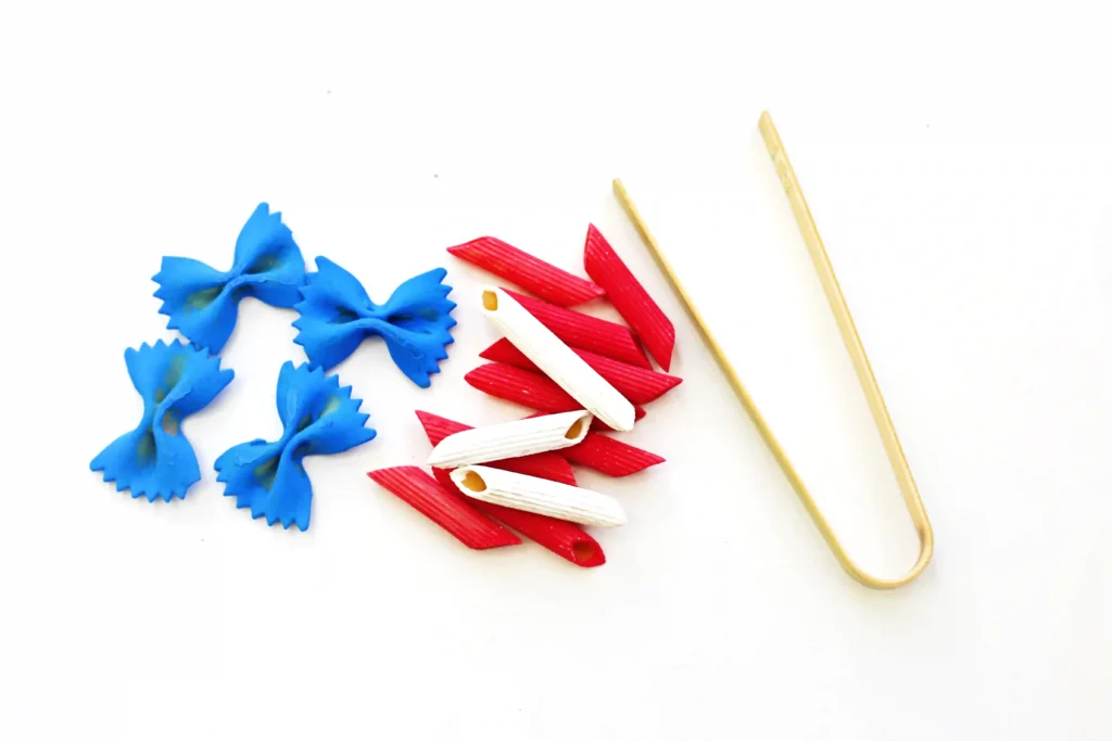 pasta dyed blue, red, and white, next to tongs