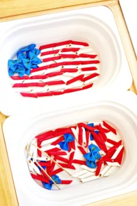 Assorted tricolor pasta (red and white tubes) with blue bow-tie pasta in a white container next to a container with the pasta arranged as an american flag
