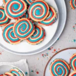 red white and blue swirled patriotic pinwheel cookies with sprinkles on the sides on a white plate