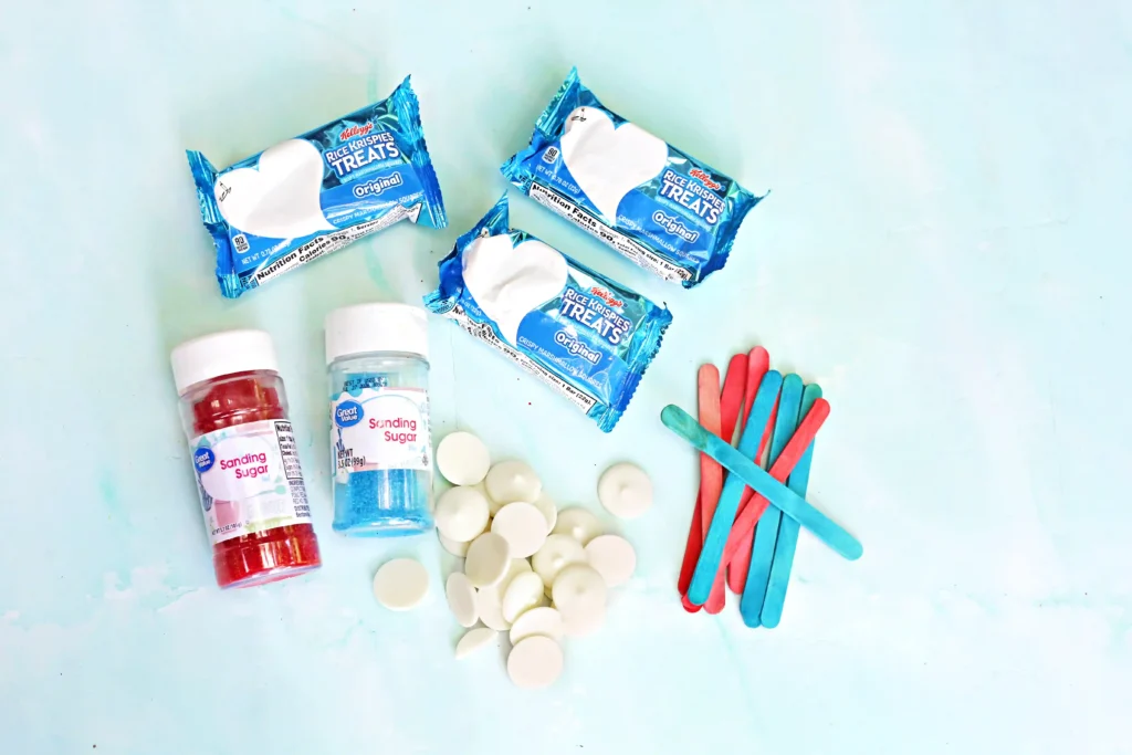 Patriotic Rice Krispie Pops - Cultivating Brilliant Minds ingredients for the Patriotic Rice Krispie Pops- rice krispie teats, popsicle sticks, red and blue sprinkles, white melting chocolate
