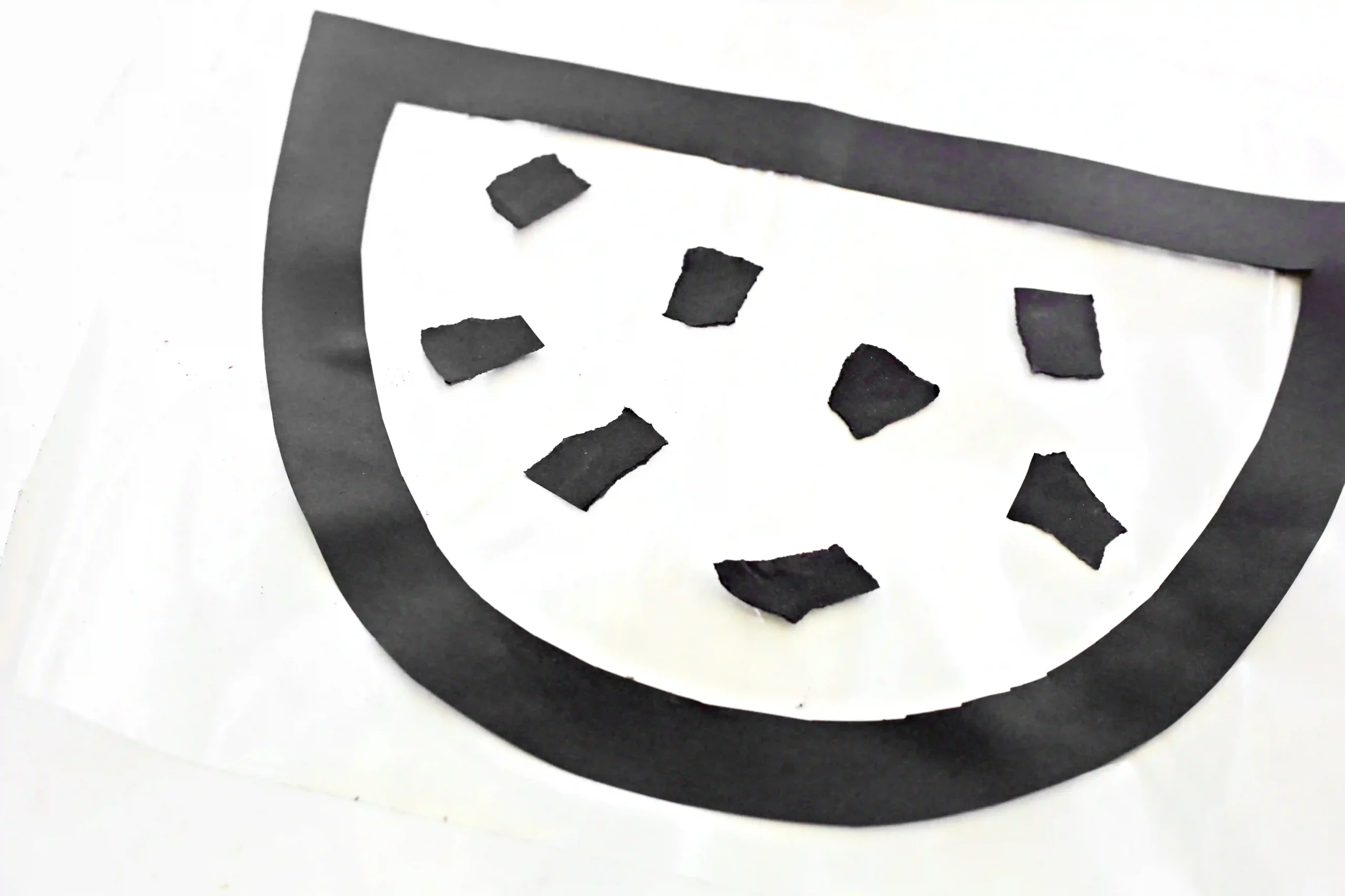 black construction paper outline with black scraps of paper in the middle