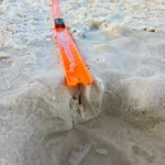 a toy car race track with a car on it in the sand at the beach