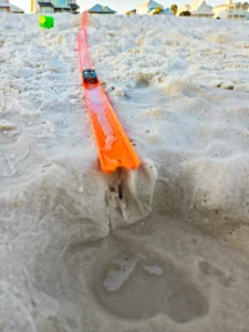 a toy car race track with a car on it in the sand at the beach