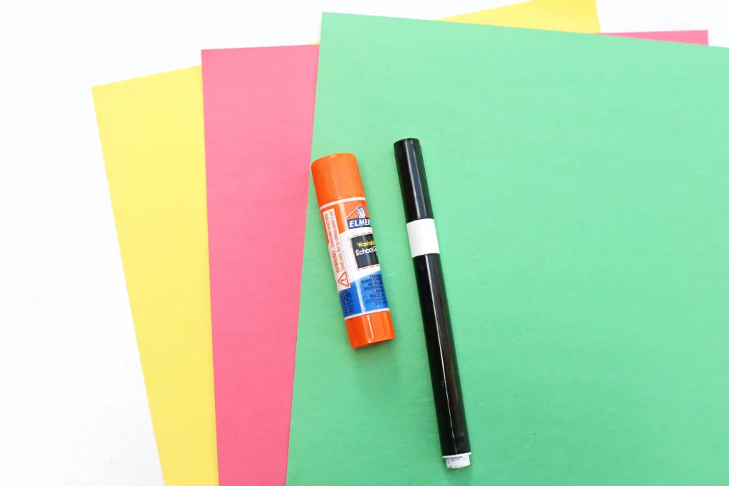 yellow, red, and green construction paper with a glue stick and black marker on top
