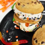 spooky ice cream sandwiches made with chocolate chip cookies, vanilla ice cream, gummy worms, and halloween sprinkles